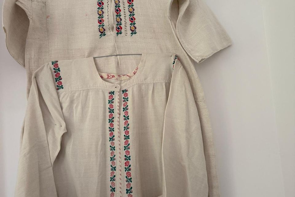 Două cămăși albe cu broderie, expuse pe perete