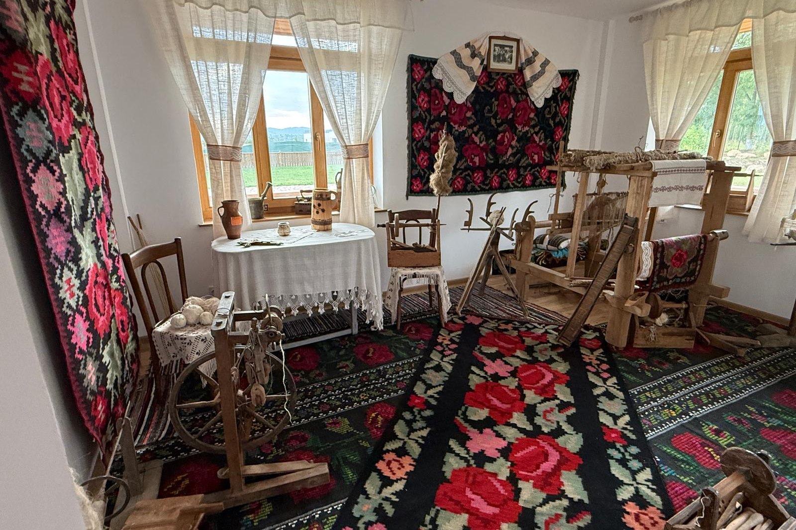 Război de țesut din lemn în sala de etnografie, pe covoare cu motive florale