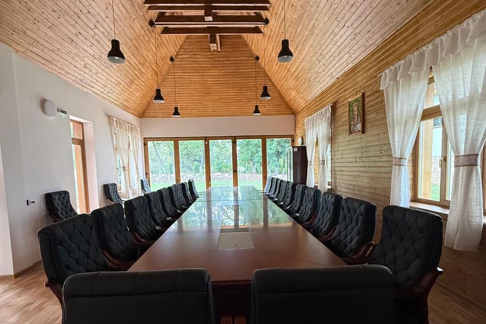 Sala multifuncțională cu masă lungă, scaune și tavan de lemn