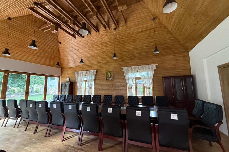 Scaune negre aliniate în sala multifuncțională cu grinzi de lemn